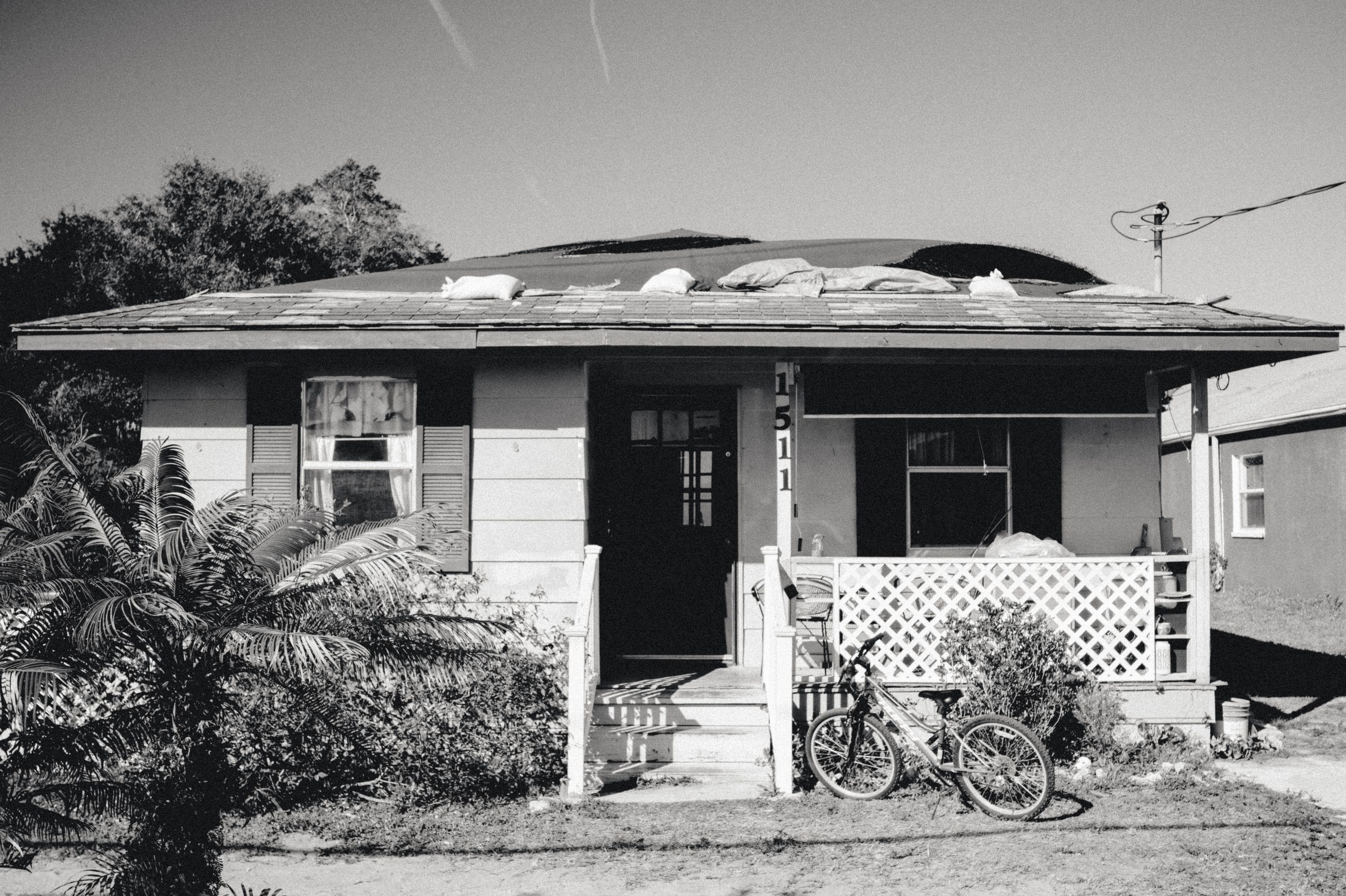 A single-story house with a porch and white lattice skirting. A bicycle leans against the front.